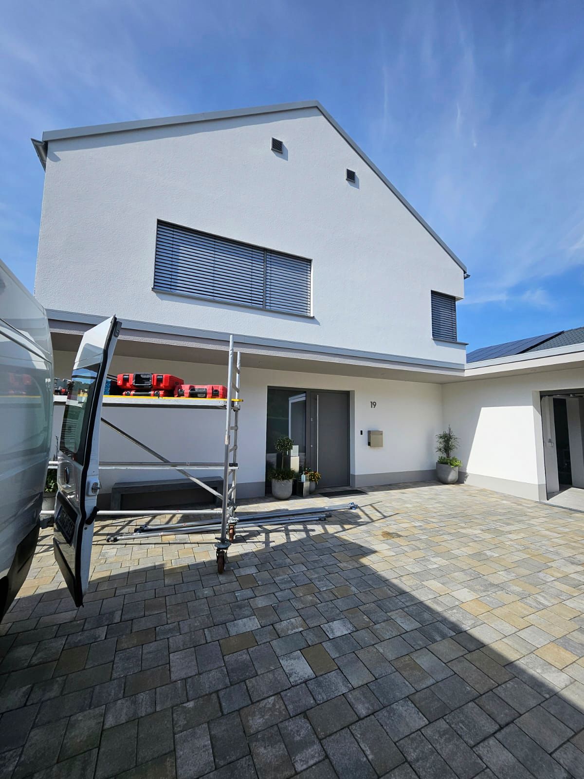 Ein weißer Lieferwagen parkt vor einem großen weißen Gebäude.