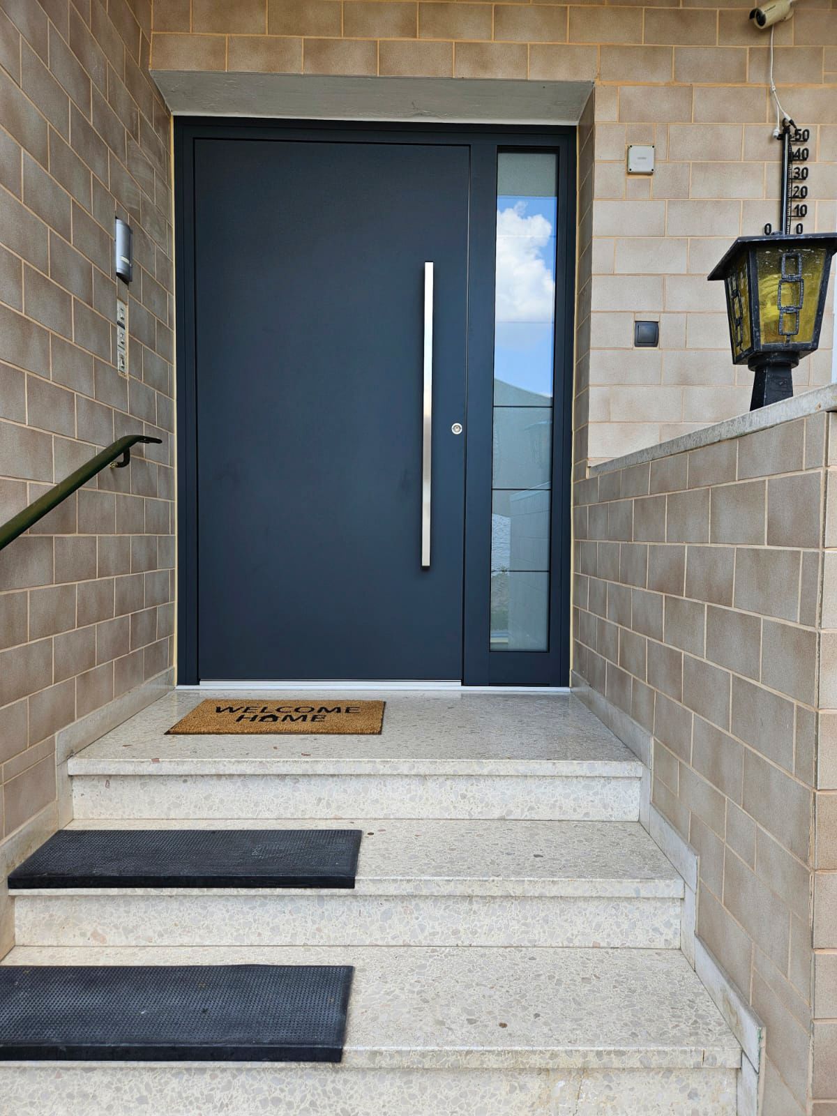 Eine schwarze Tür mit einem Glasfenster und einer Treppe, die dorthin führt