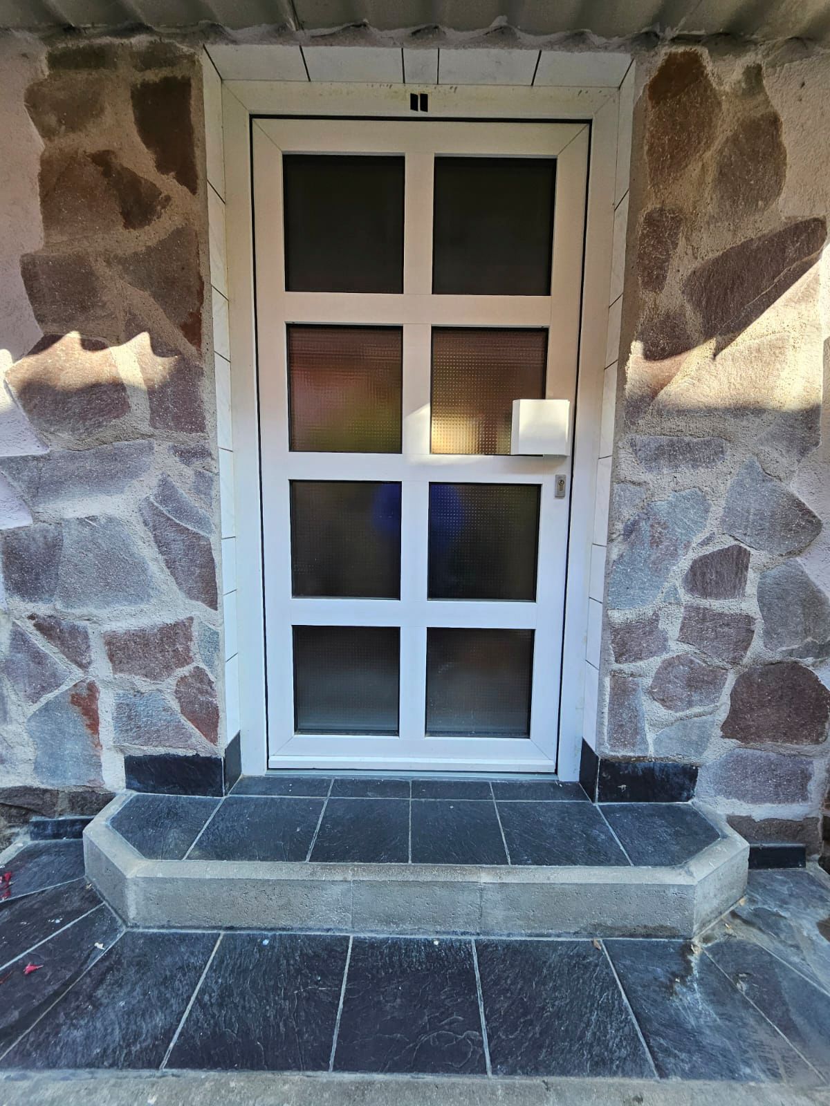 Eine weiße Tür mit einer Steinmauer dahinter