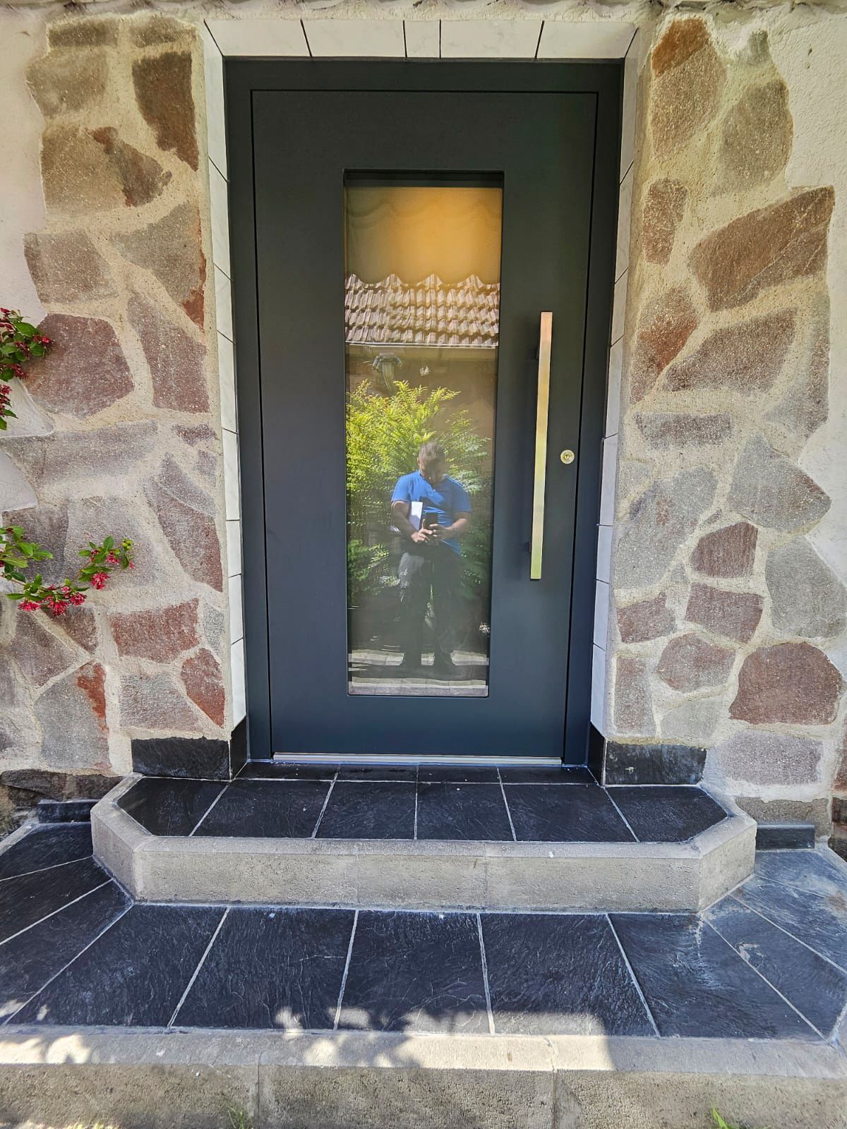 Eine Steinmauer mit einer schwarzen Tür und Stufen