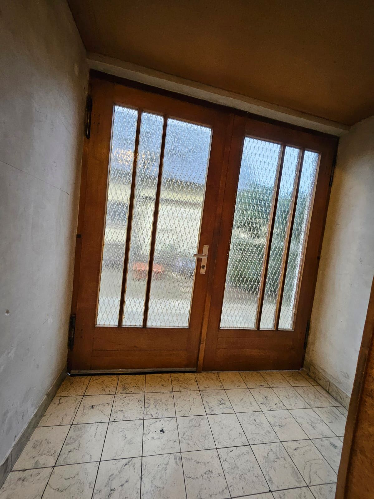 Ein Raum mit einer Holztür und einem Fliesenboden.