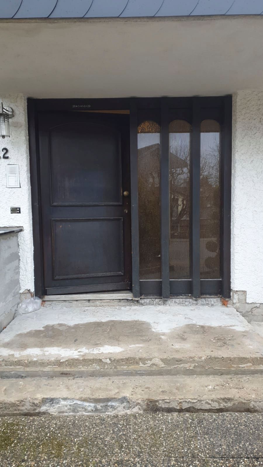 Die Haustür eines Hauses mit einer schwarzen Tür und Stufen.