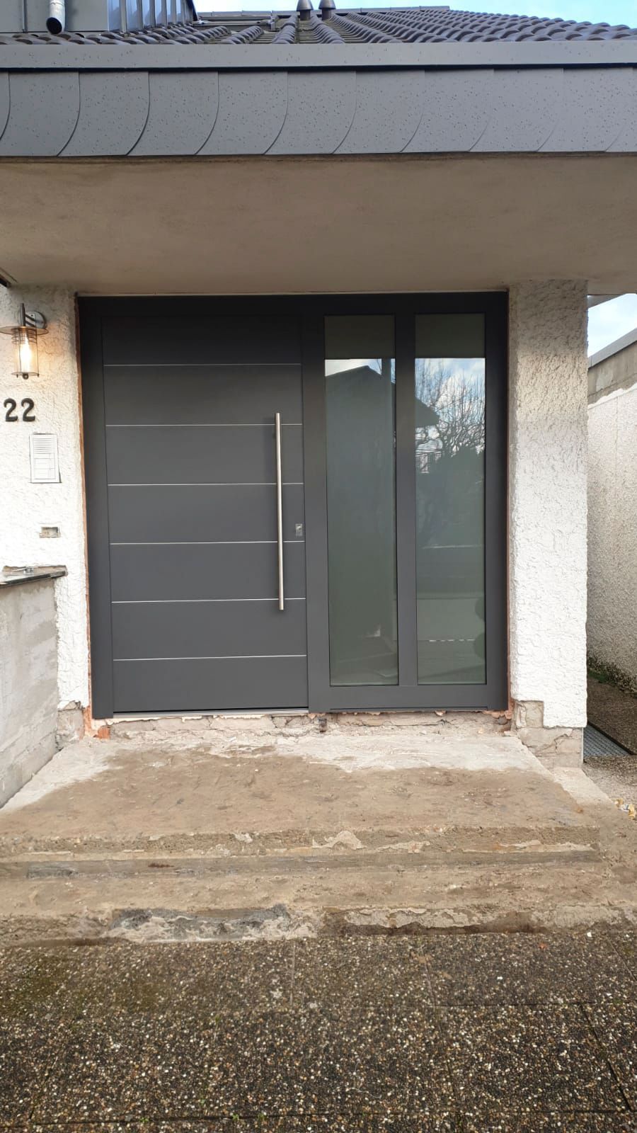 Die Haustür eines Hauses mit einer grauen Tür und einer Glastür.