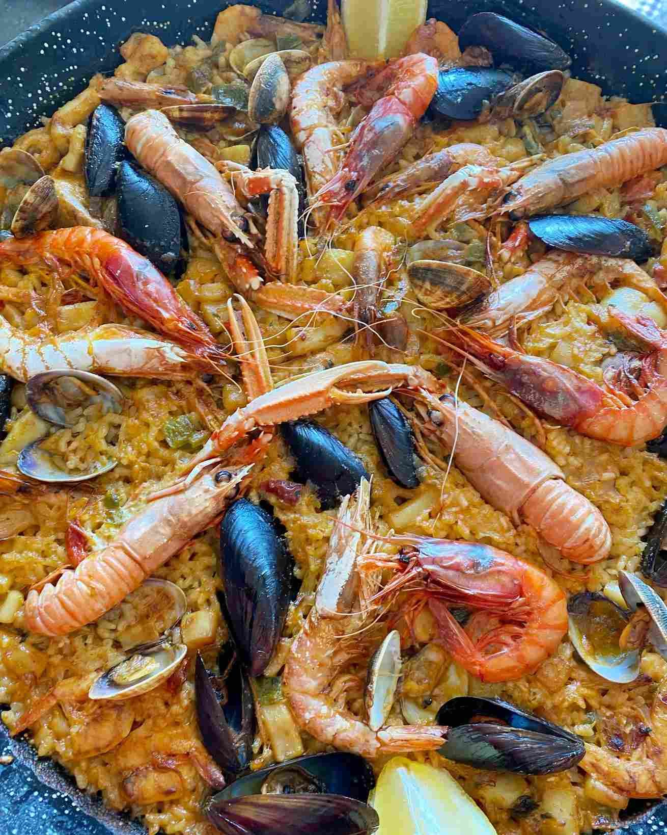 Paella de marisco con mejillones, gambas, almejas y arroz en una sartén.