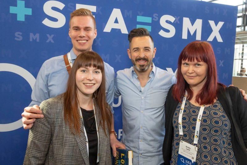 Oikiolaiset SMX-tapahtumassa sinisen brändätyn taustan edessä