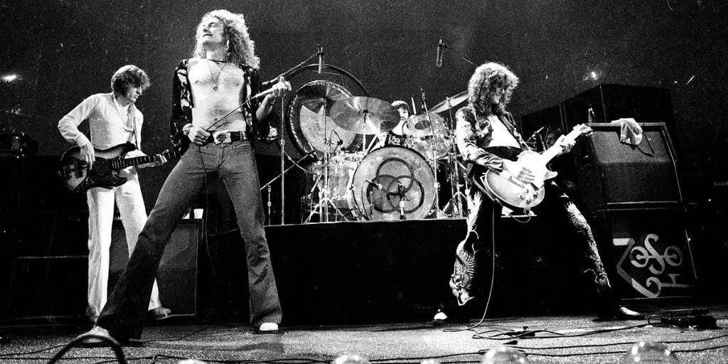 Mustavalkoinen valokuva rock-yhtyeestä esiintymässä lavalla kitaroiden ja rumpujen kanssa