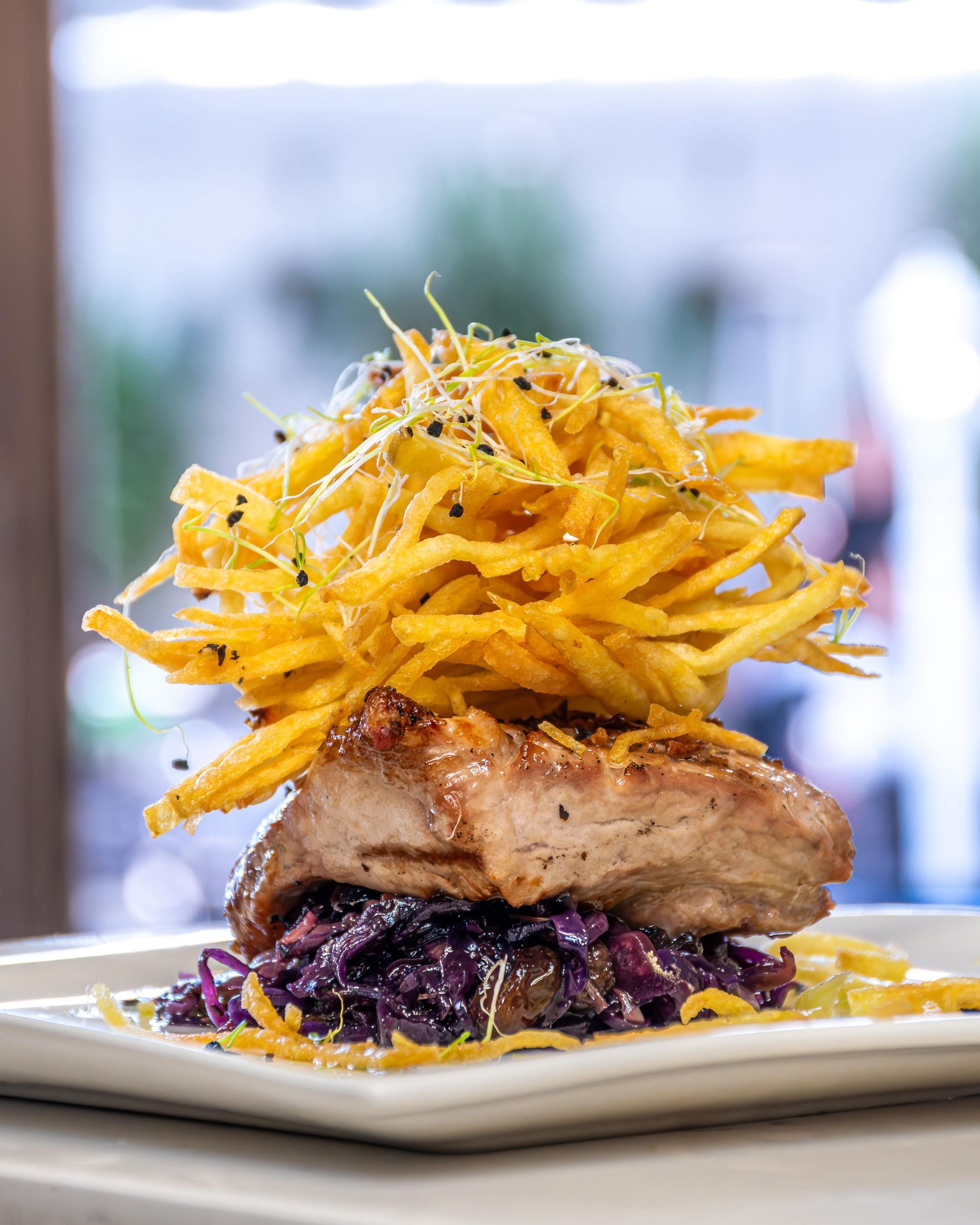 Una persona sostiene un plato de postre con salsa de chocolate y azúcar en polvo.
