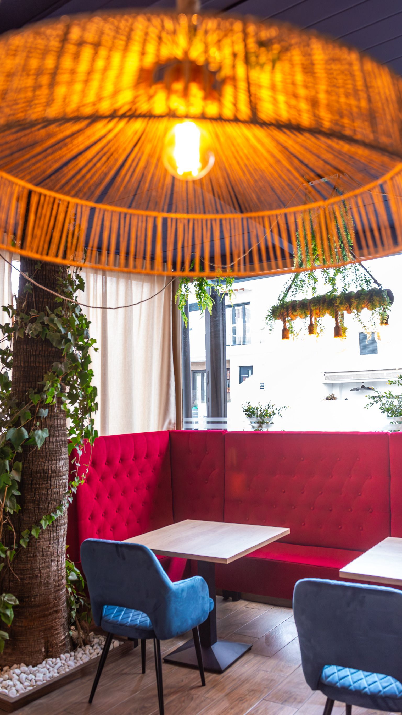 Un restaurante con un sofá rojo, sillas y mesas azules.