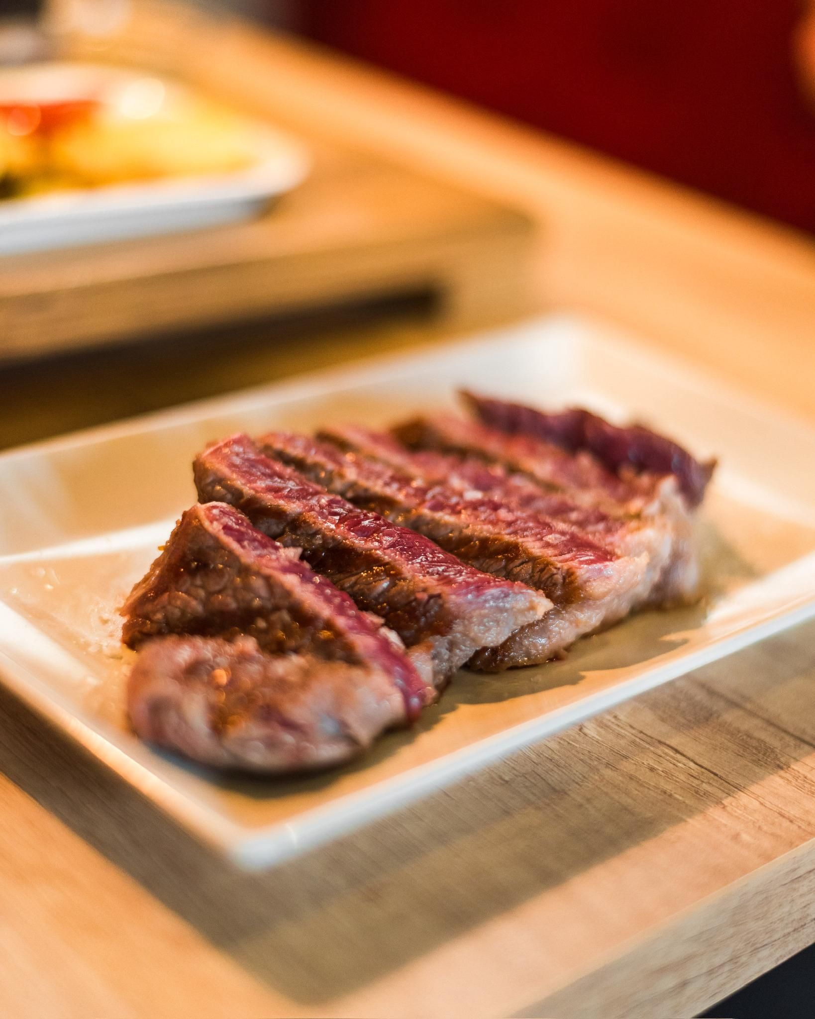 Un filete está sentado en un plato blanco sobre una mesa de madera.