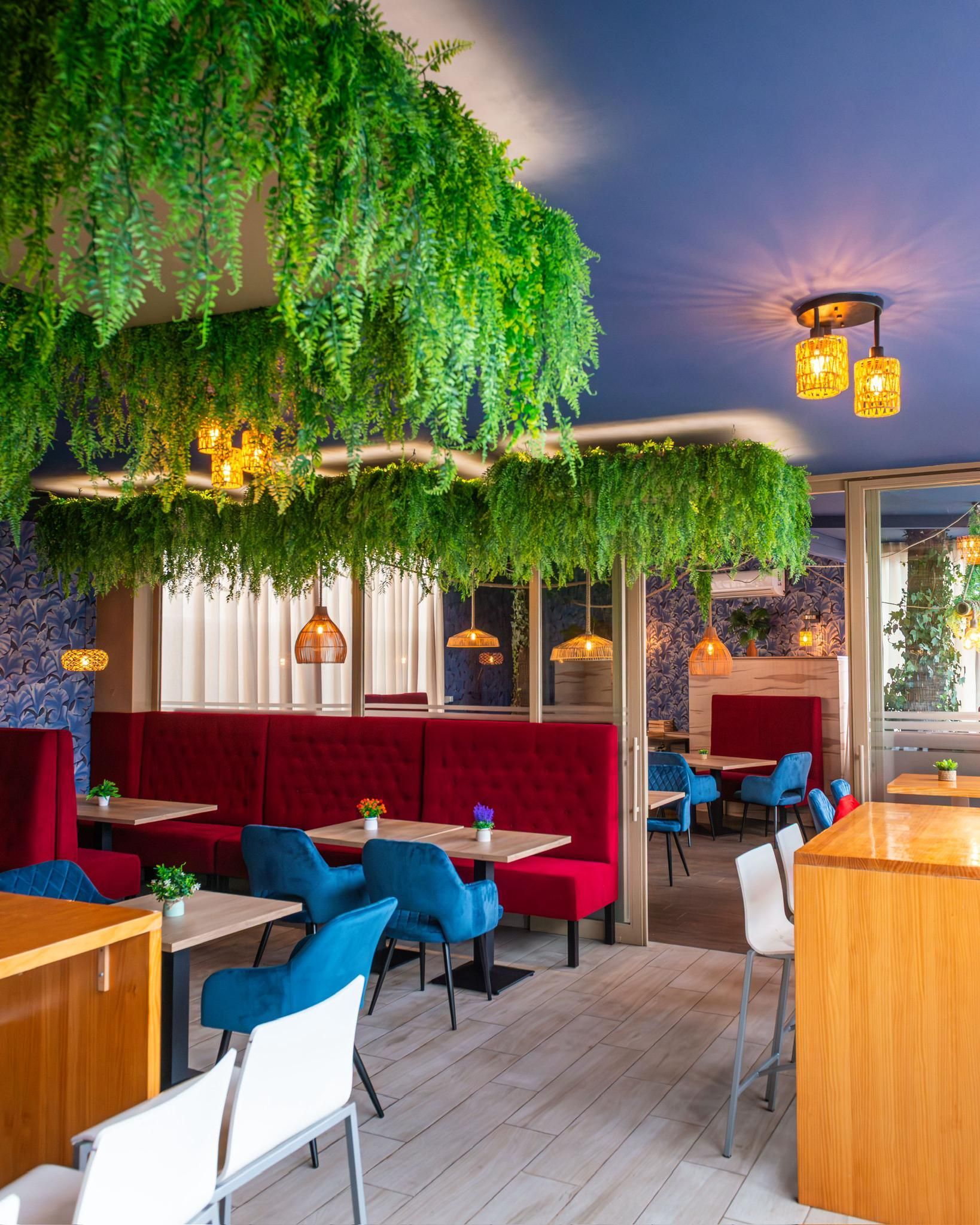 Un restaurante con mesas y sillas y plantas verdes colgando del techo.