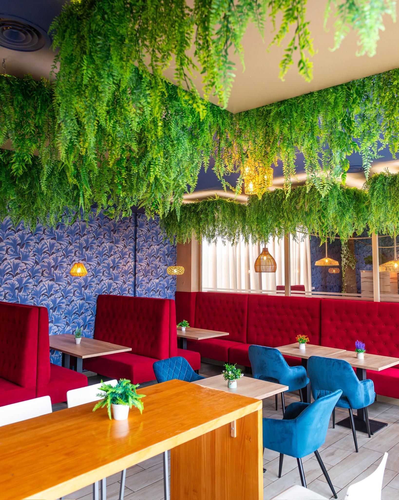 Un restaurante con mesas y sillas y plantas colgando del techo.