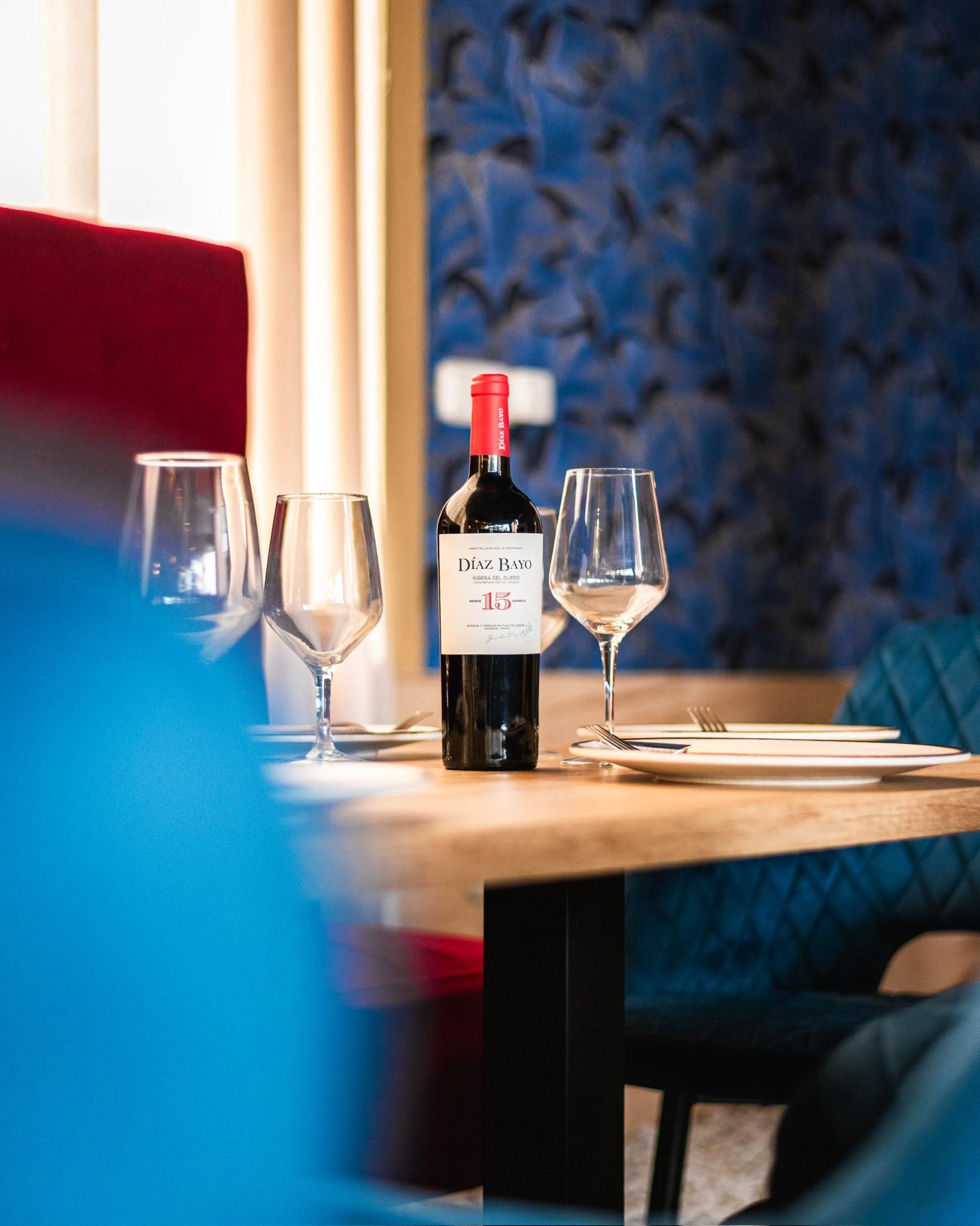 Una botella de vino está sobre una mesa al lado de copas de vino.