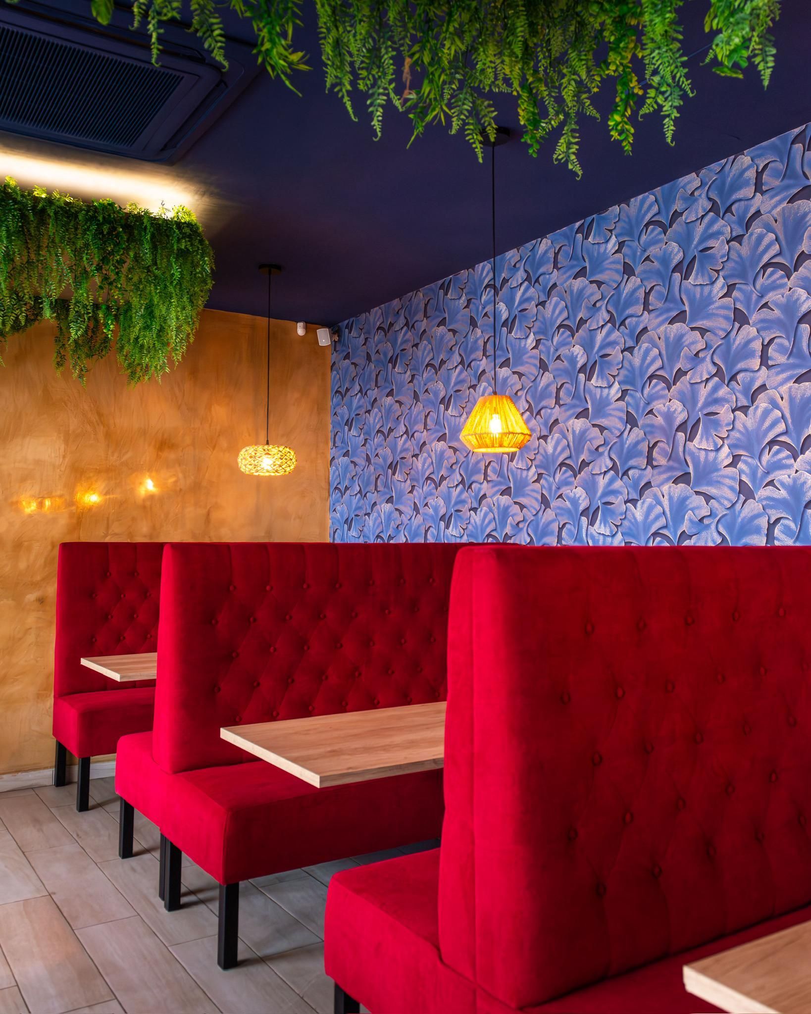 Una fila de cabinas rojas con mesas en un restaurante.