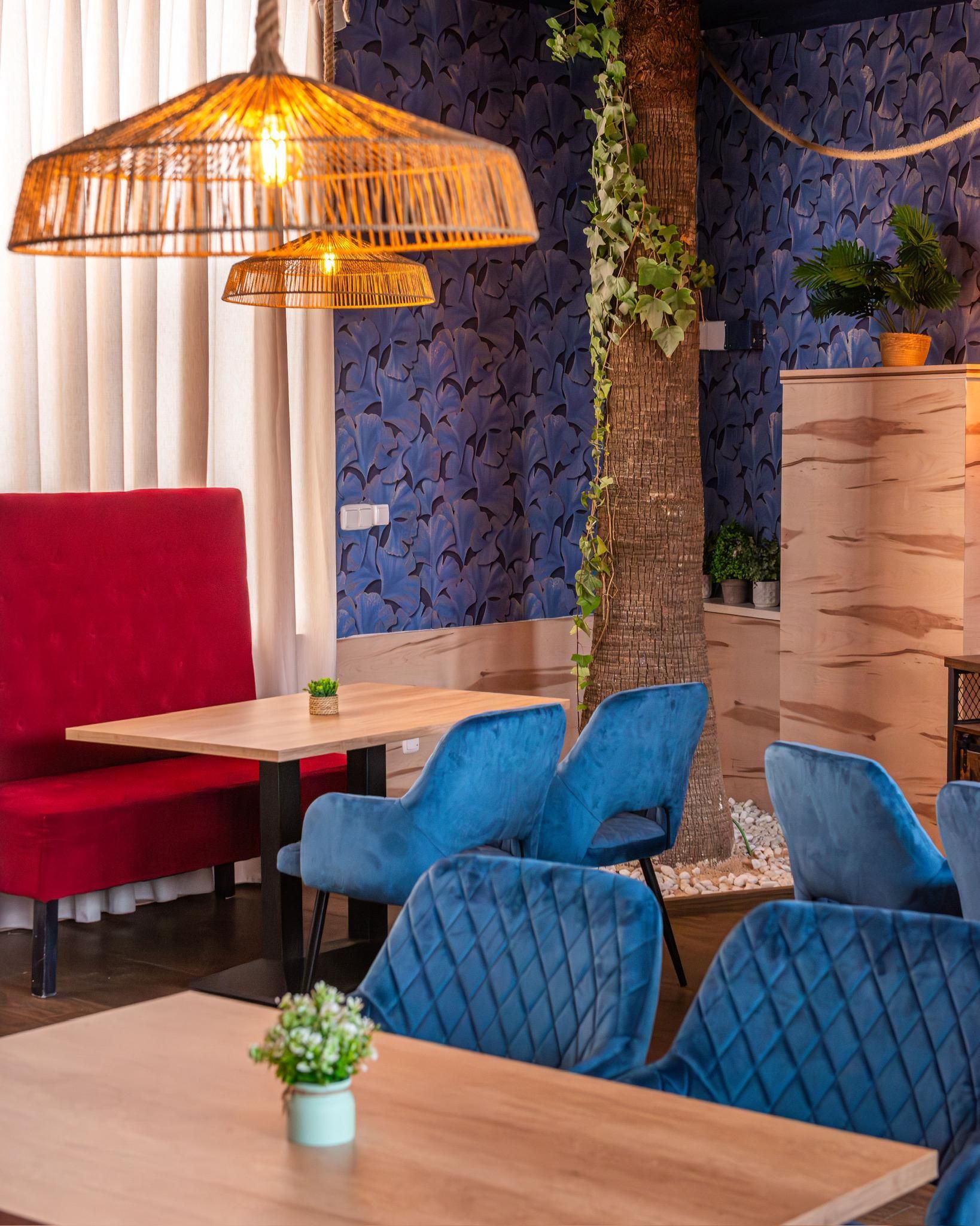 Un comedor con mesas y sillas y un banco rojo.