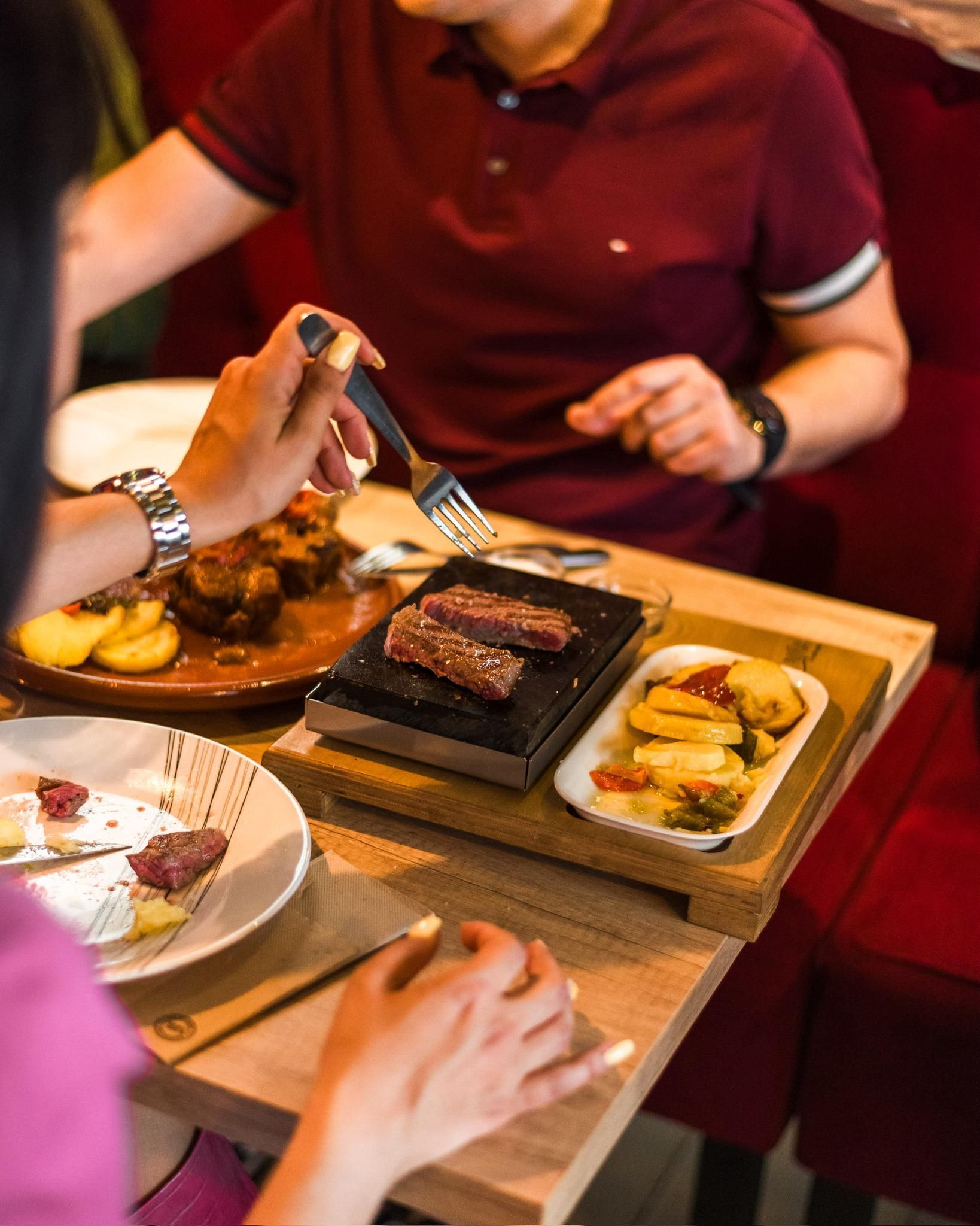 Un hombre y una mujer están sentados en una mesa comiendo comida.