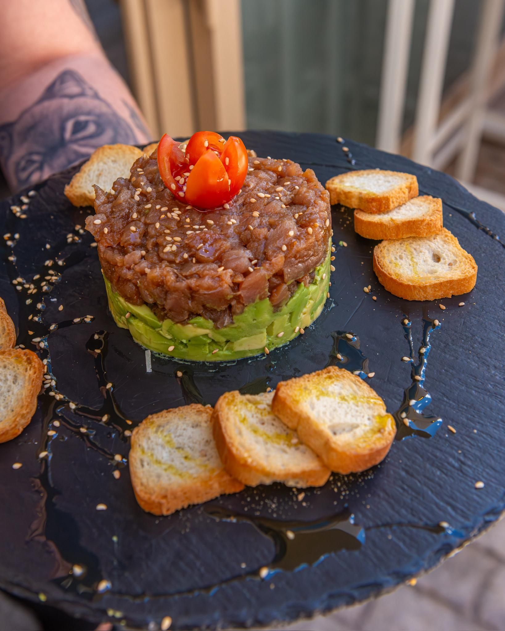 Una persona sostiene un plato de comida con aguacate y crutones.