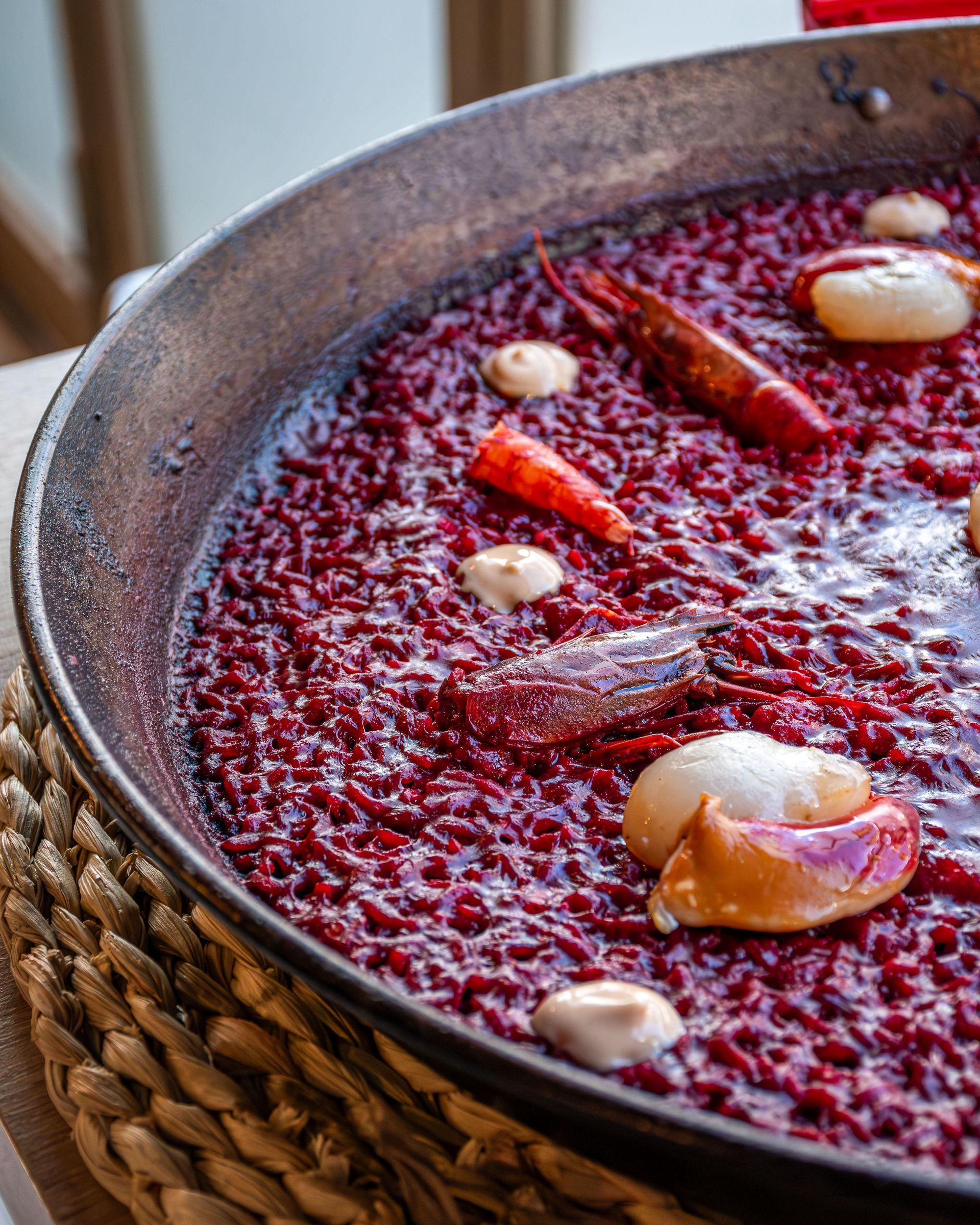 Paella con arroz rojo, mariscos y pimientos en una sartén grande y redonda.