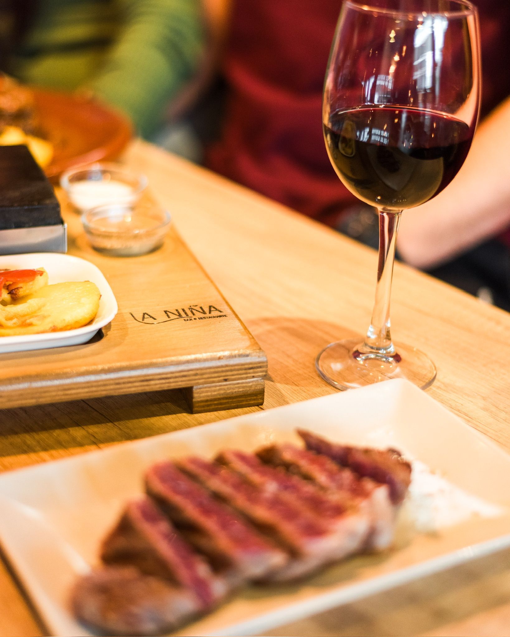 Un plato de carne y una copa de vino en una mesa