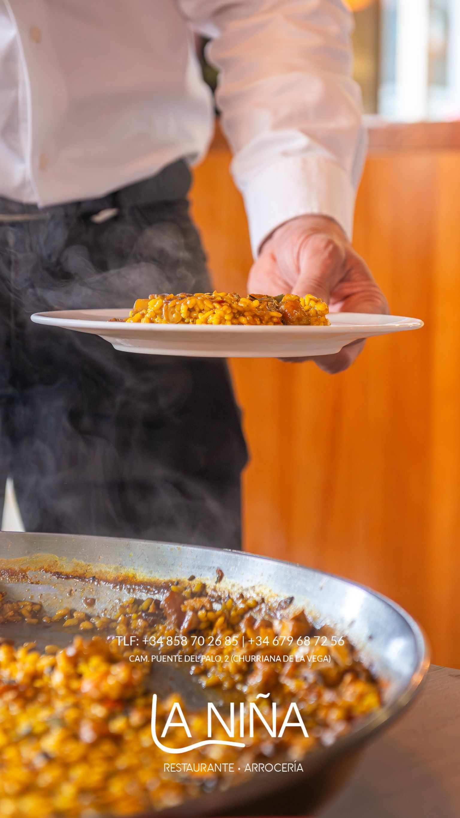 Un hombre sostiene un plato de comida delante de una sartén con comida.