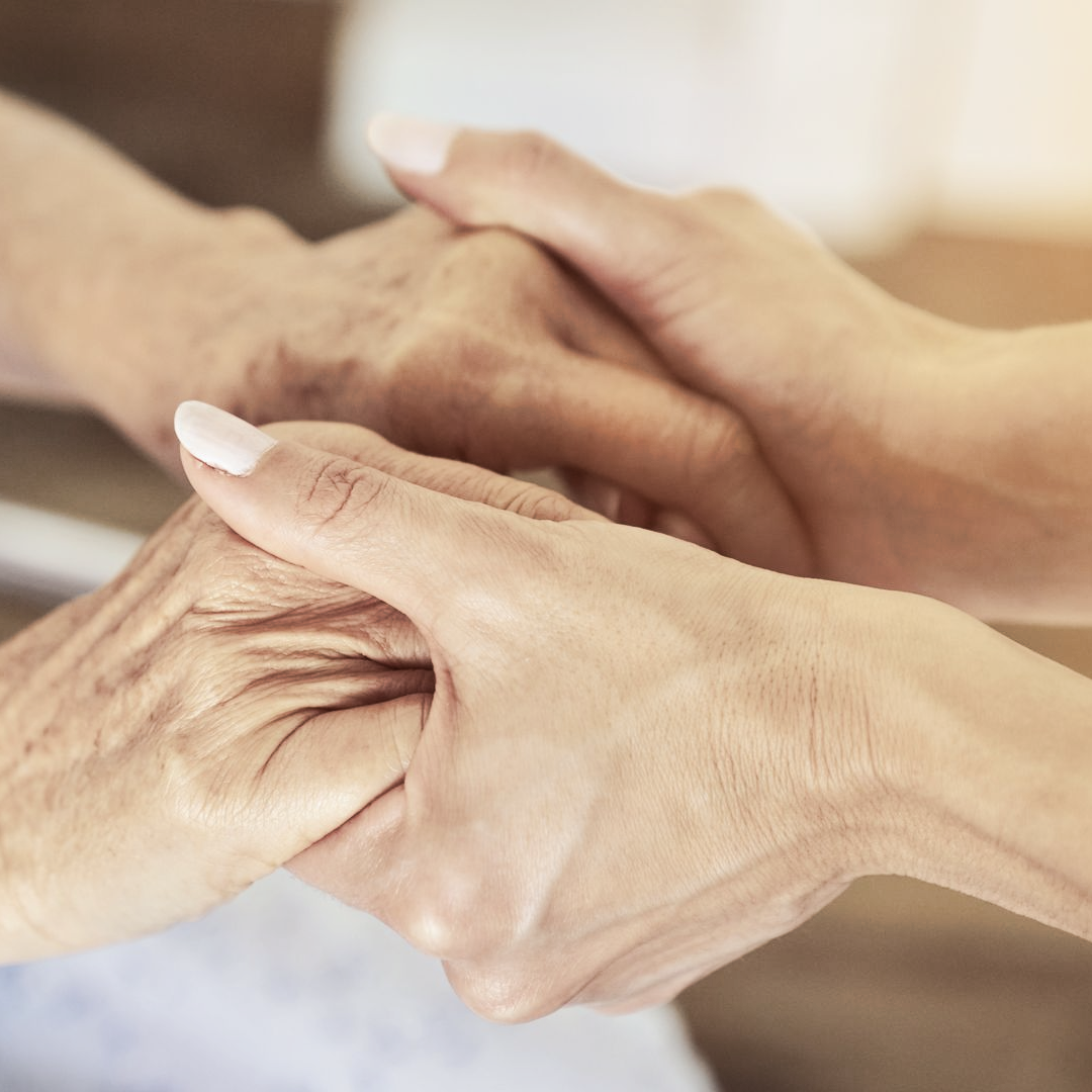Deux mains tenant délicatement les mains ridées d'une autre personne, symbolisant le soutien et l'attention.