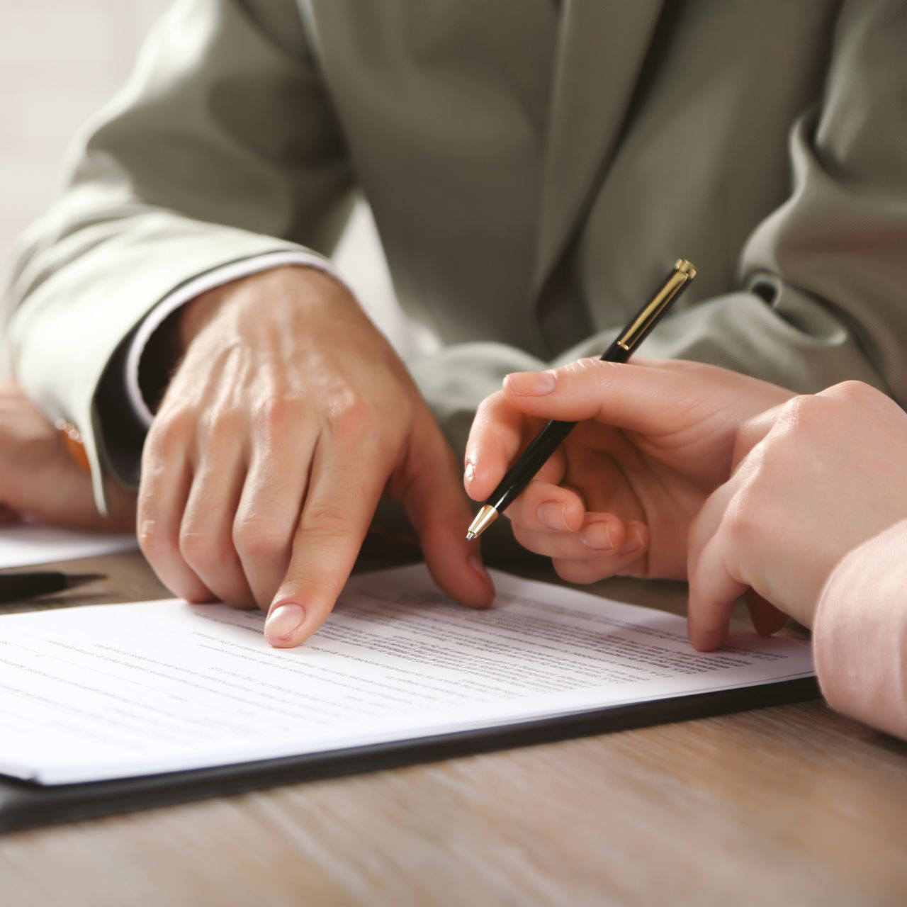 Deux personnes en tenue professionnelle examinent ensemble un document, l'une pointant du doigt et l'autre tenant un stylo.