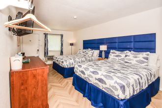 A hotel room with a king size bed , desk , chairs and a window.