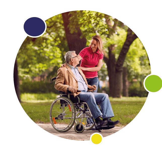 Une personne âgée en extérieur dans un fauteuil roulant regarde la personne qui l'aide