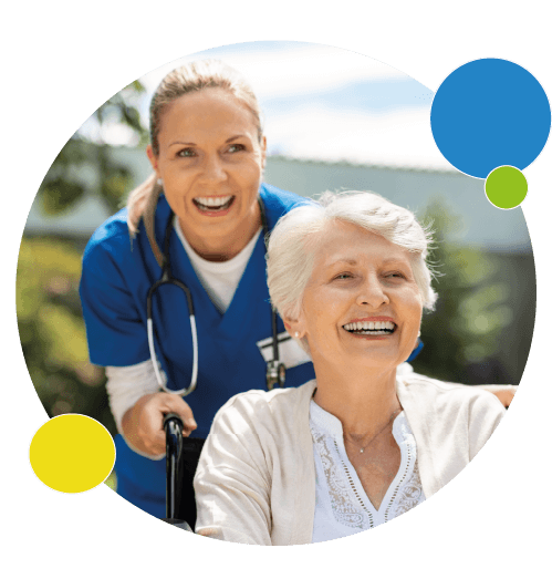 Une femme âgée dans un fauteuil roulant sourit avec une infirmière souriante