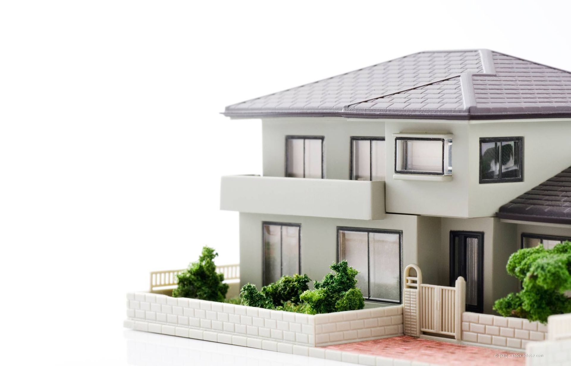 Modellhaus mit grauem Dach und hellgrünen Wänden vor weißem Hintergrund.