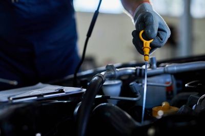Un mécanicien utilise un tournevis pour travailler sur le moteur d'une voiture sous le capot.