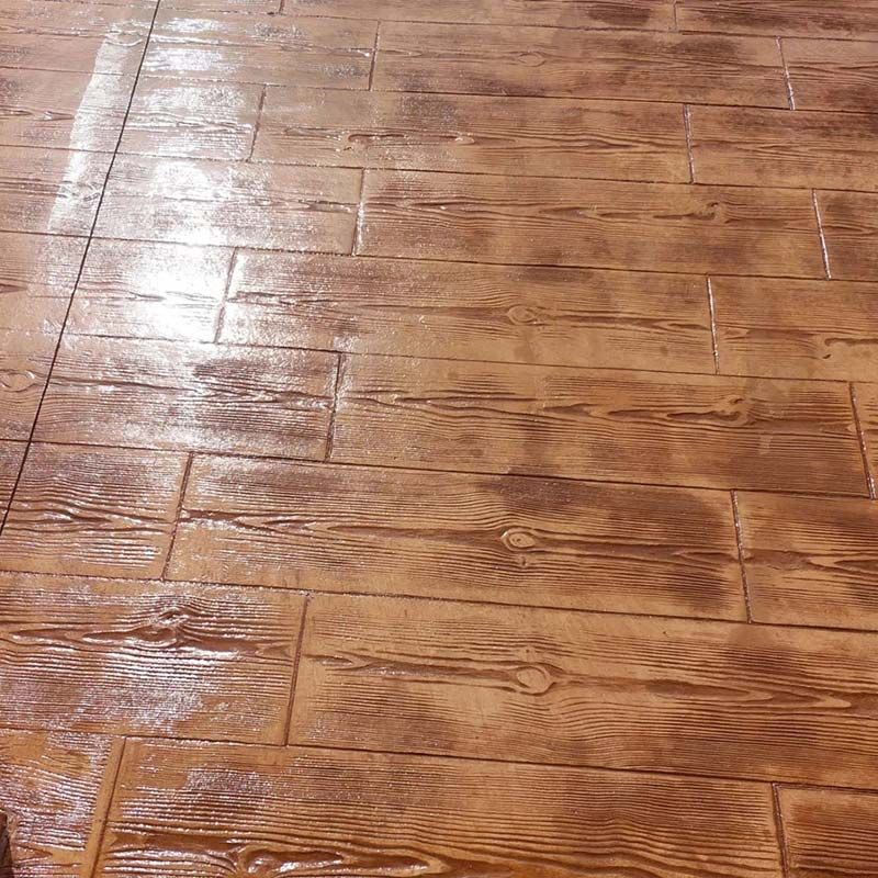 Piso de hormigón estampado diseñado para parecerse a tablones de madera, en tonos marrones.
