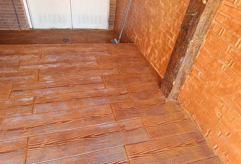 Piso de tablones de madera en una habitación con paredes con textura similar al ladrillo a juego y una viga de soporte de madera.