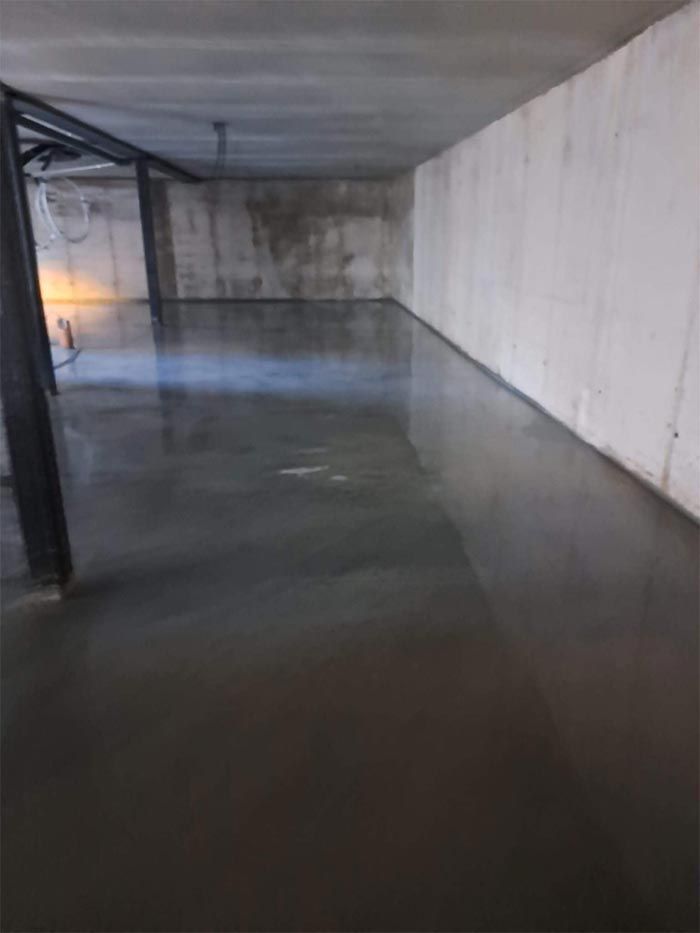 Sótano vacío con suelo de hormigón gris y pared de hormigón blanco.