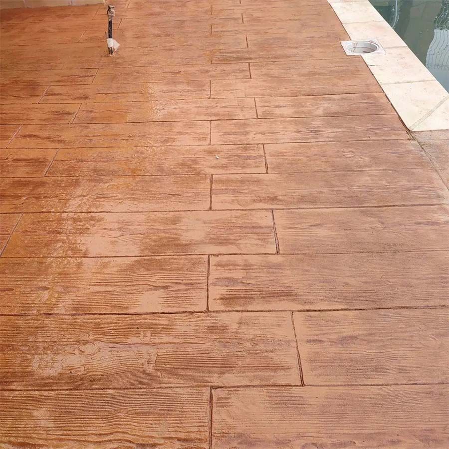 Patio de hormigón estampado con diseño de tablones de madera, color marrón cálido.