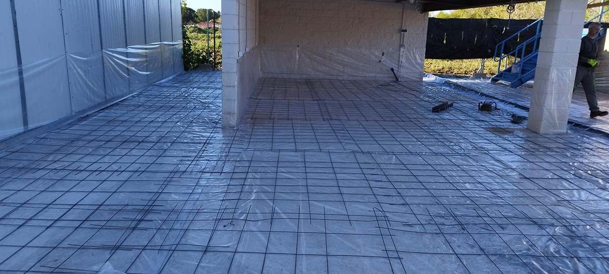 Sitio de construcción con rejilla de varillas de refuerzo colocada en el suelo, lista para verter el hormigón.