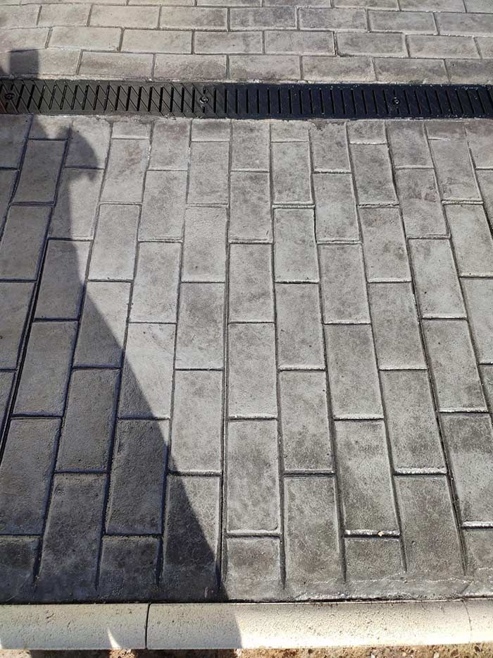 Pavimento de ladrillo gris con desagüe.