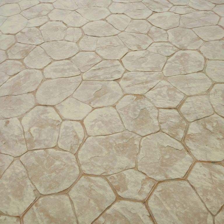 Pavimento de hormigón estampado con dibujo de piedra irregular, en tonos tostados y marrones.