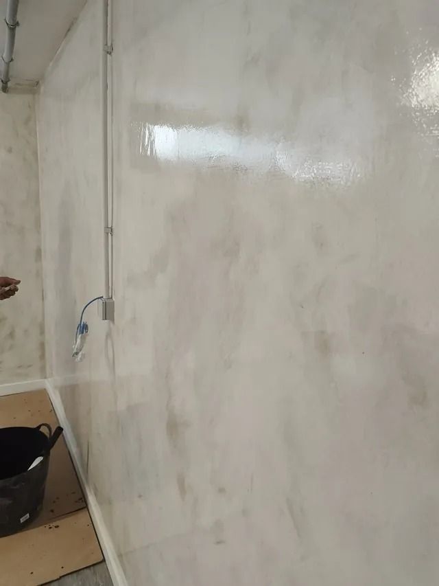 Una persona está pintando una pared blanca en una habitación.