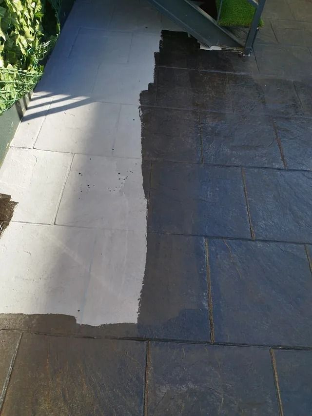 Una escalera se refleja en un charco de agua en una acera.