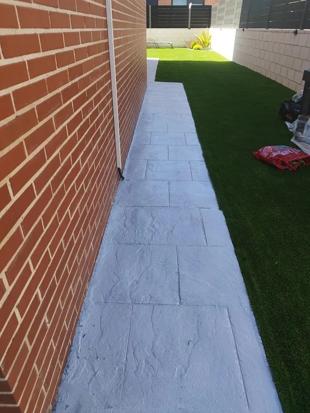 Una pared de ladrillos con una acera delante