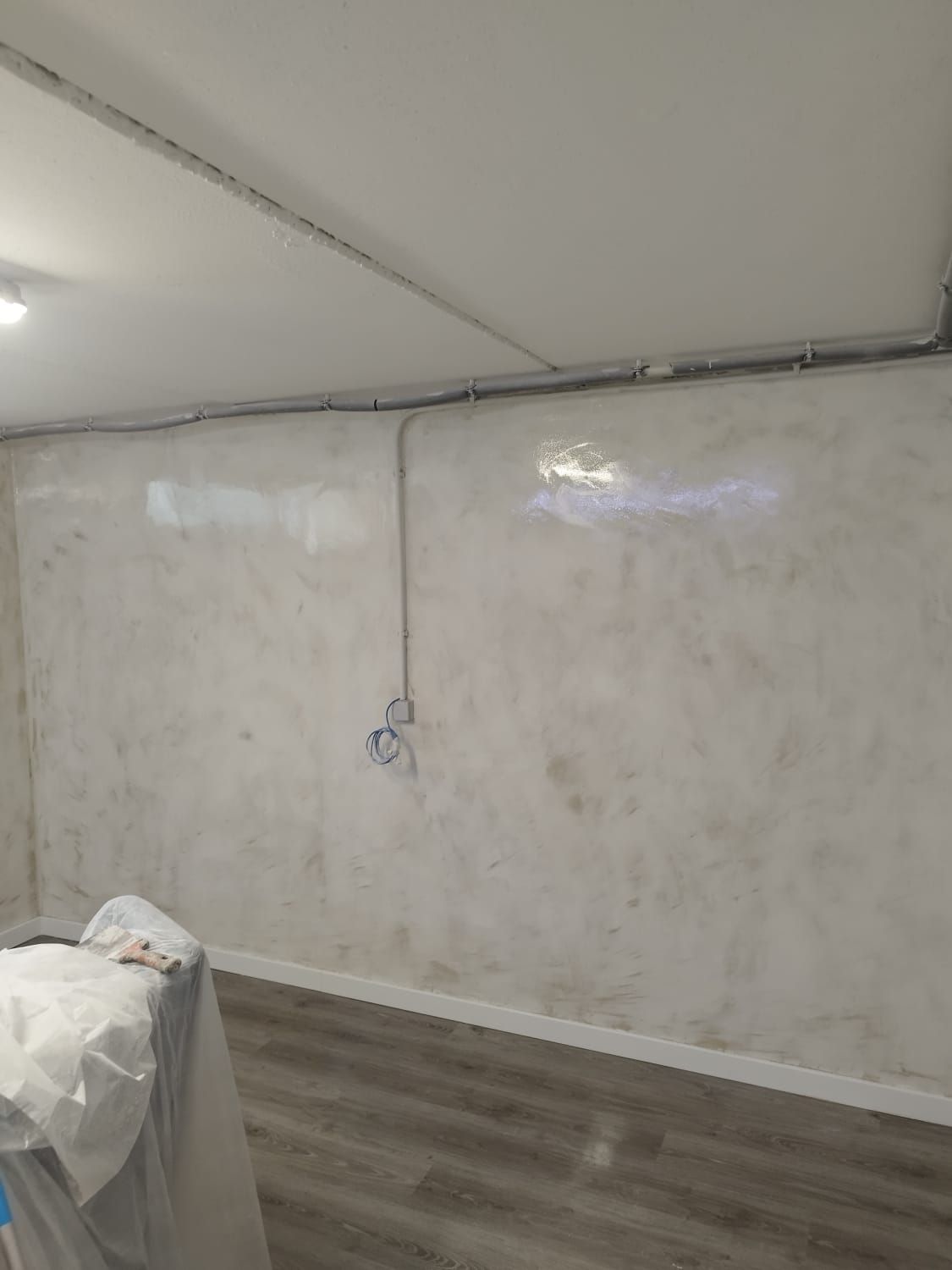 Una habitación con una pared blanca y un suelo de madera.