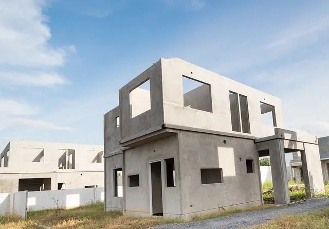 Se está construyendo una casa de hormigón en un campo con un cielo azul de fondo.