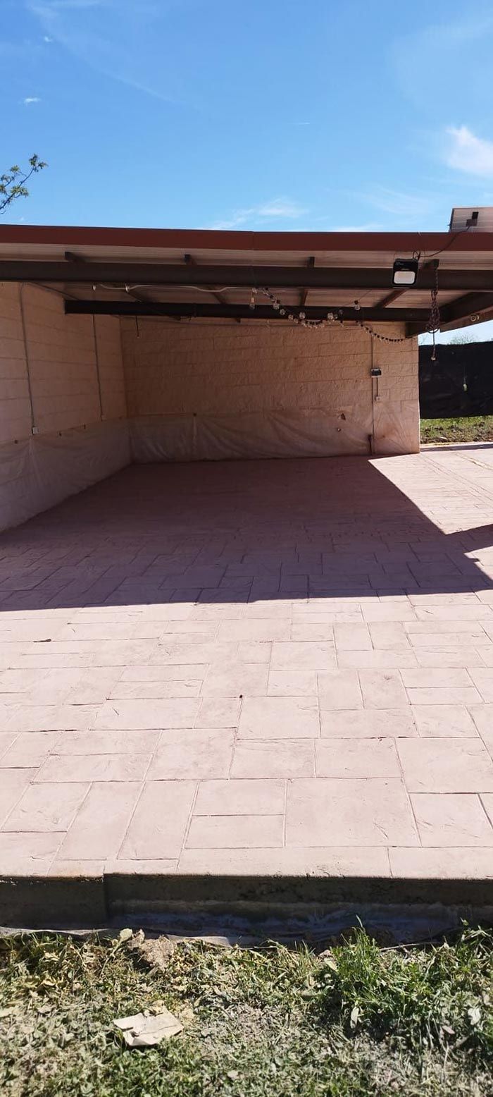 Estructura al aire libre con piso de ladrillo y techo de metal contra un cielo azul.