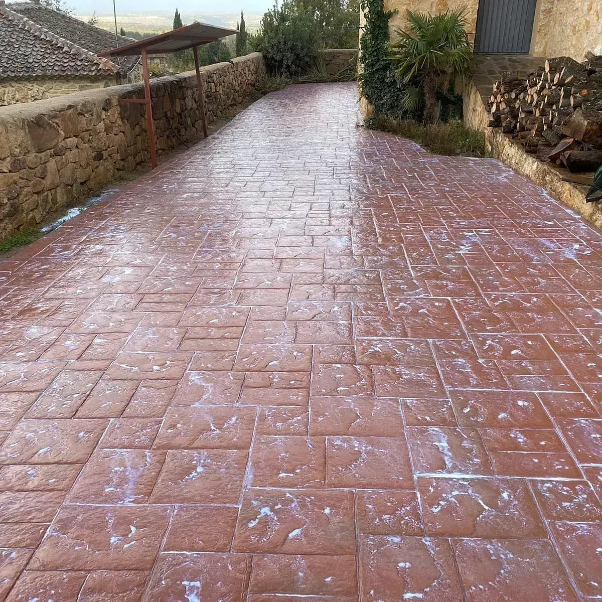 Un camino de entrada de ladrillo con un muro de piedra a lo largo del costado.
