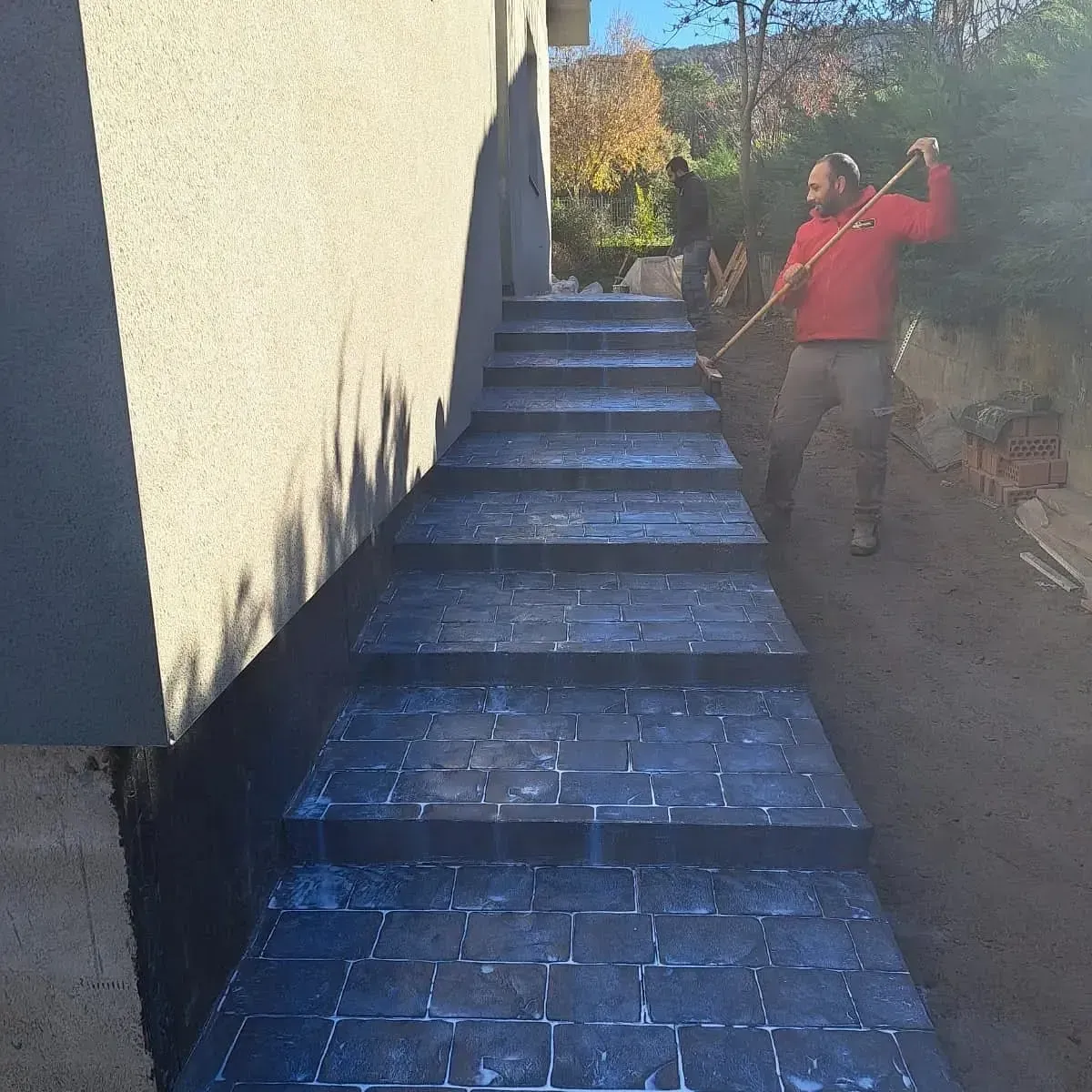 Un hombre de pie en unas escaleras sosteniendo una escoba.