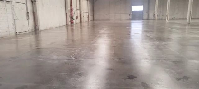 Un gran almacén vacío con suelo de hormigón y paredes blancas.