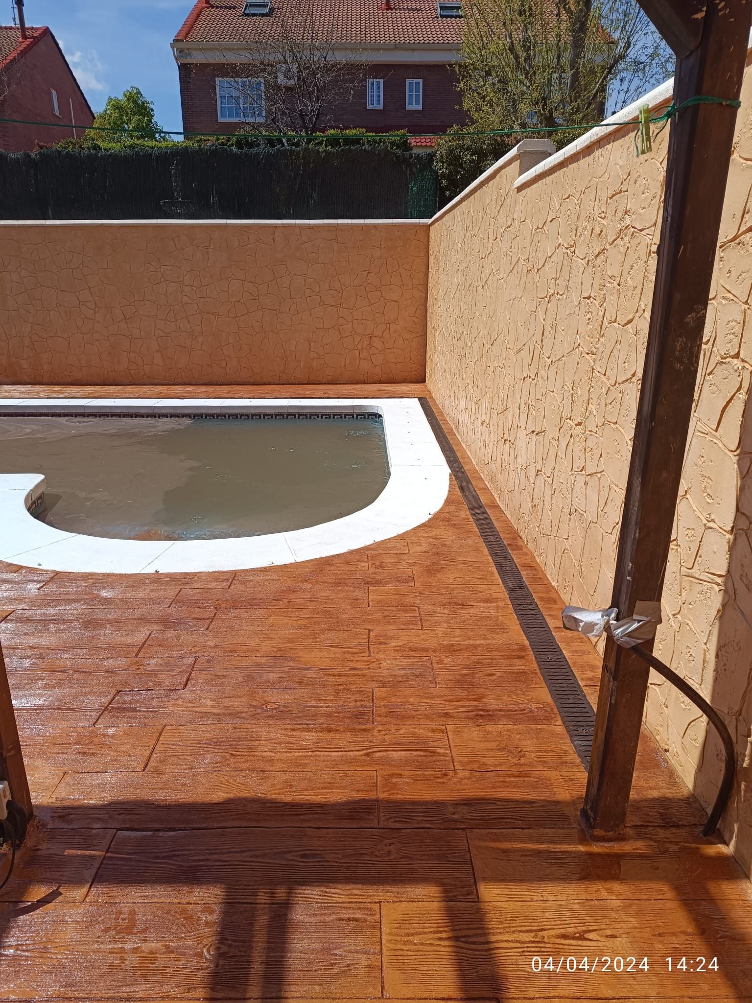 Una piscina está rodeada por un muro y una terraza de madera.
