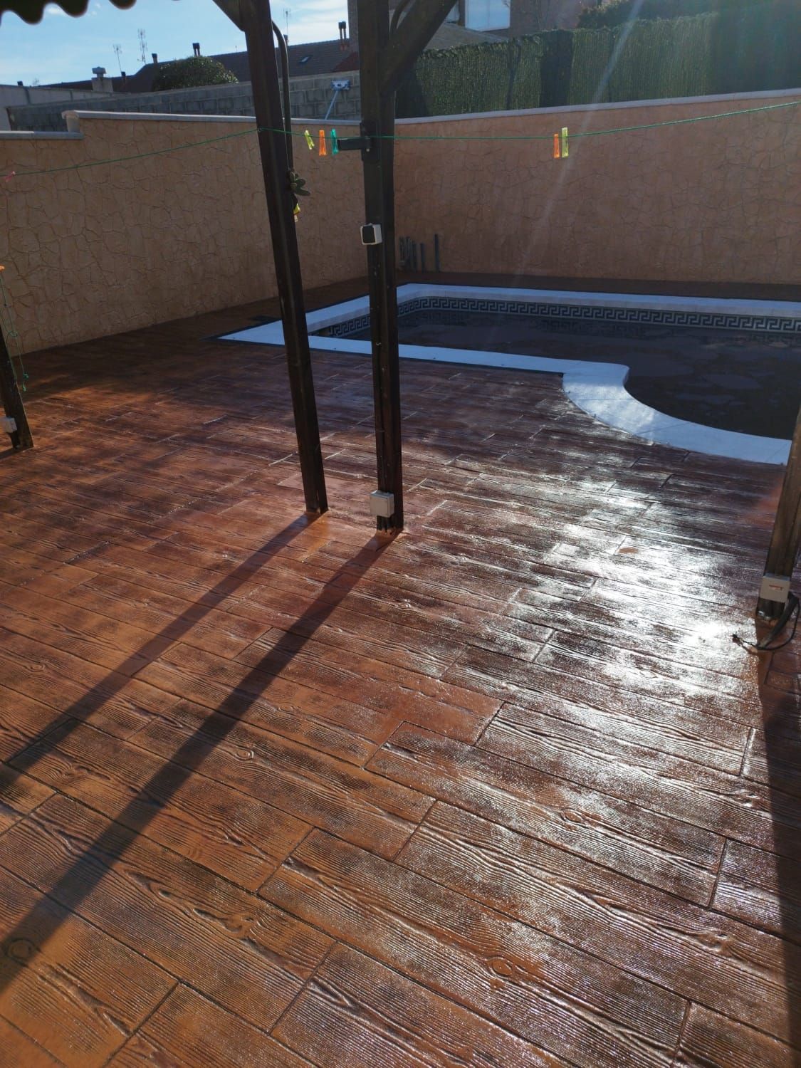 Un patio con pérgola y una piscina al fondo.