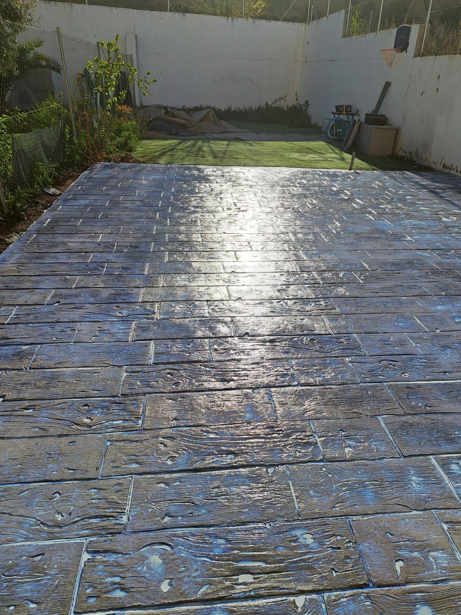 Un camino de entrada de ladrillos en un patio trasero con el sol brillando sobre él.