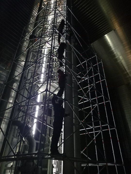 Montage d’échafaudage de nuit par des ouvriers le long d'une tour